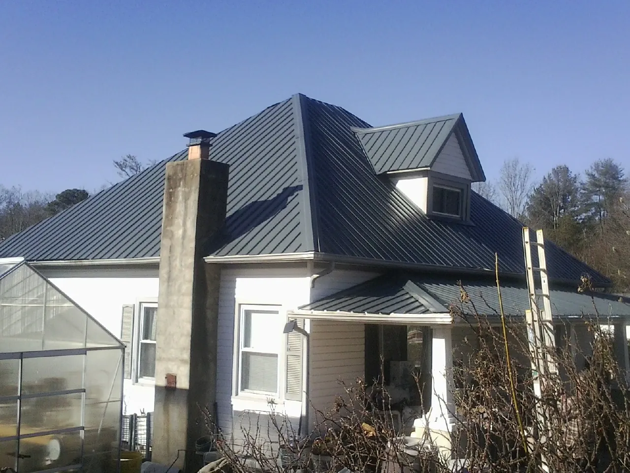 Dark blue standing seam metal roof on a white farmhouse with dormer — Slate & Tile Roof Repair by Roofing Brothers in Lancaster